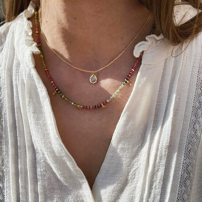 Collana di tomalina indossata con una catena dorata e diamante solitarioe argento placcato oro